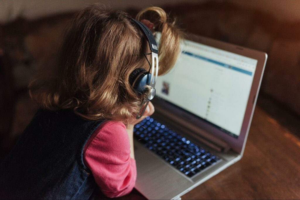 Young kid uses a computer with headphones